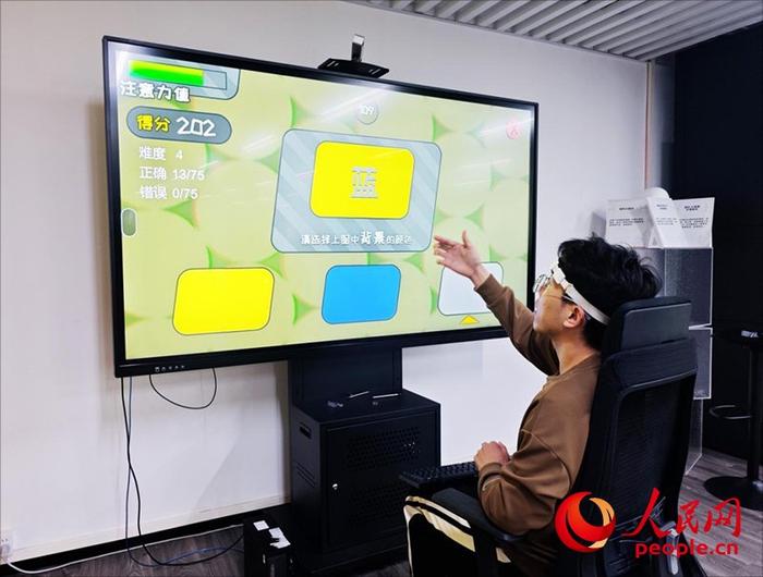 广州琶洲实验室工作人员演示脑机接口设备如何操作专注力训练游戏。人民网 朴馨语摄
